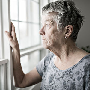 older person staring out a window